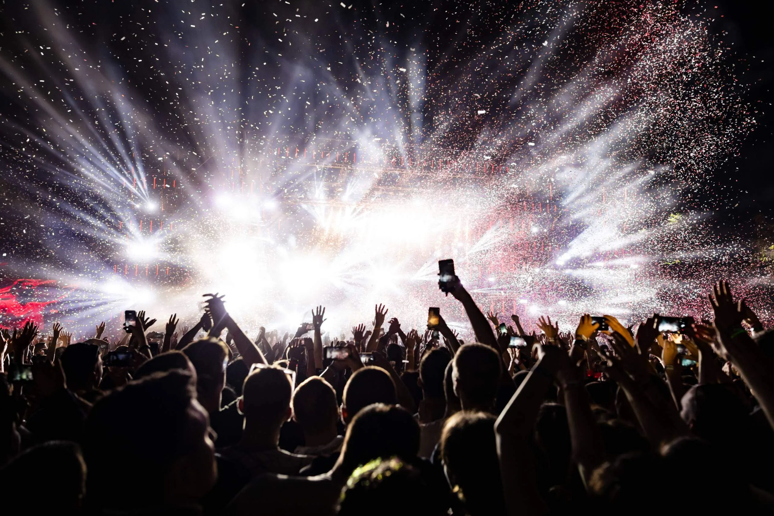 Audience recording a live event beneath stage lights and confetti